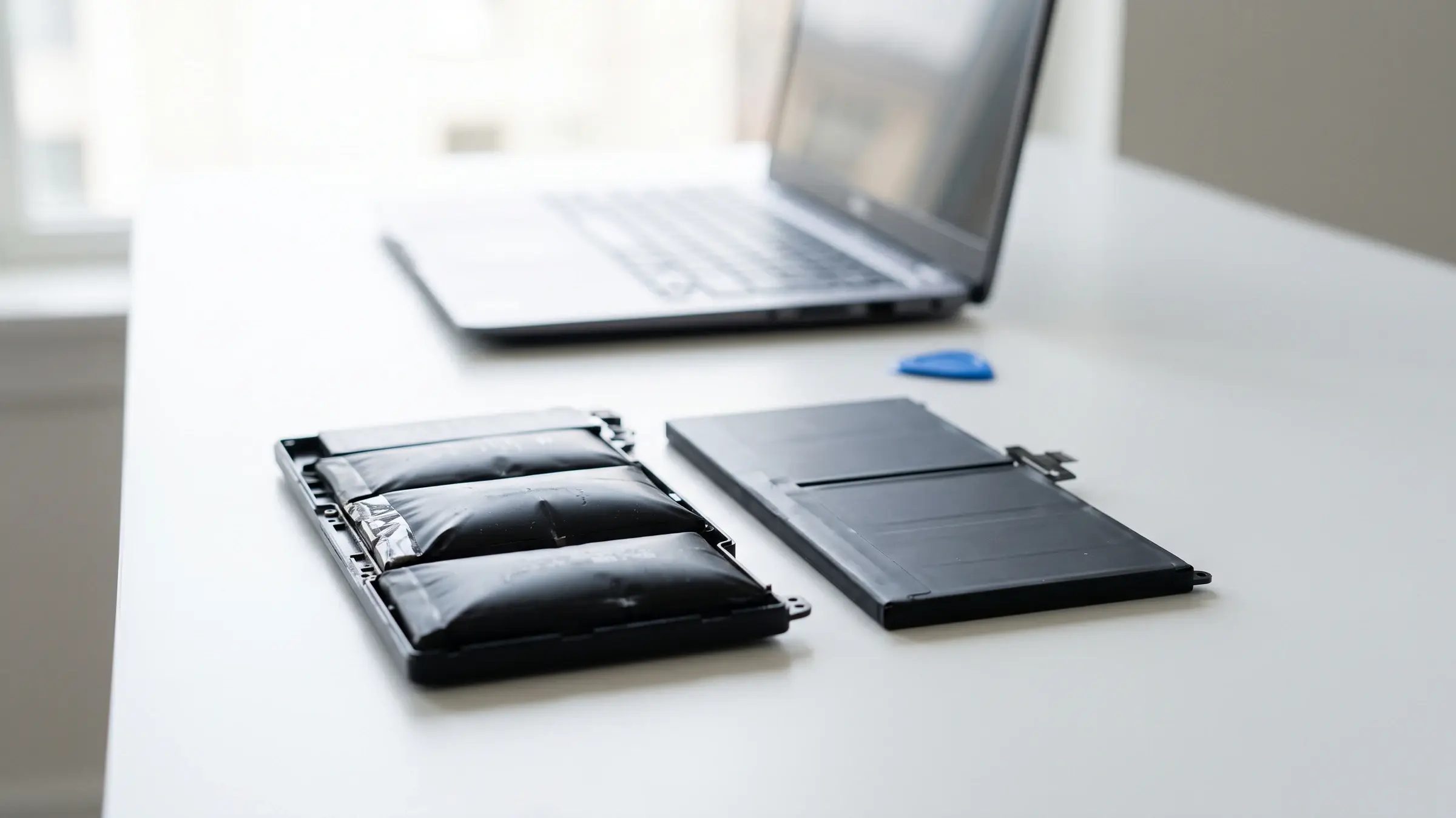 Akku-Tausch: Alter aufgeblähter Laptop-Akku neben neuem Ersatzakku beim Akku-Tausch
